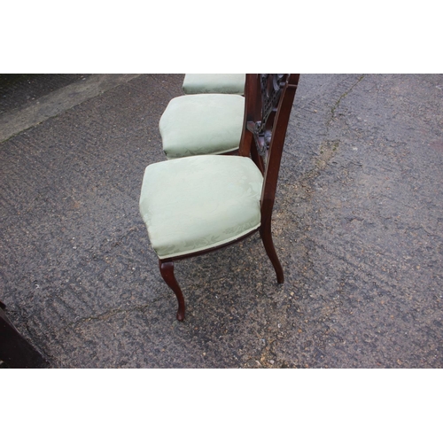 595 - A set of four Edwardian carved walnut salon chairs with pierced splat backs and stuffed over seats, ... 