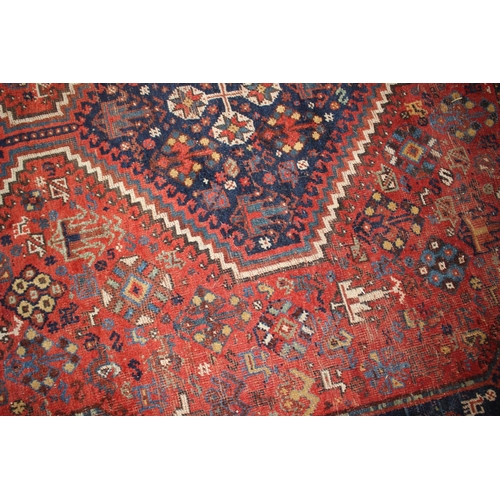 614 - A Qashqai type tribal rug with three medallions on a red ground with flowers, birds, trees and multi... 