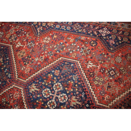 614 - A Qashqai type tribal rug with three medallions on a red ground with flowers, birds, trees and multi... 