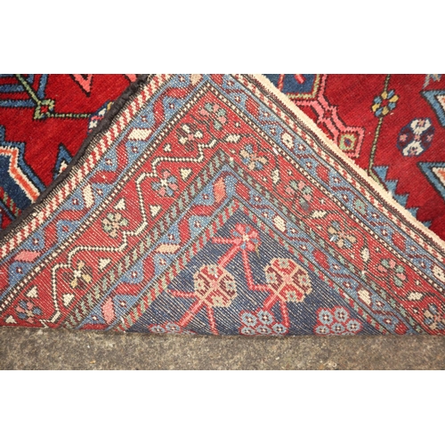 633 - A near pair of Kazak style rugs with blue central medallions on a red ground, 51