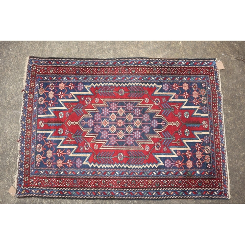 633 - A near pair of Kazak style rugs with blue central medallions on a red ground, 51