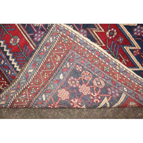 633 - A near pair of Kazak style rugs with blue central medallions on a red ground, 51