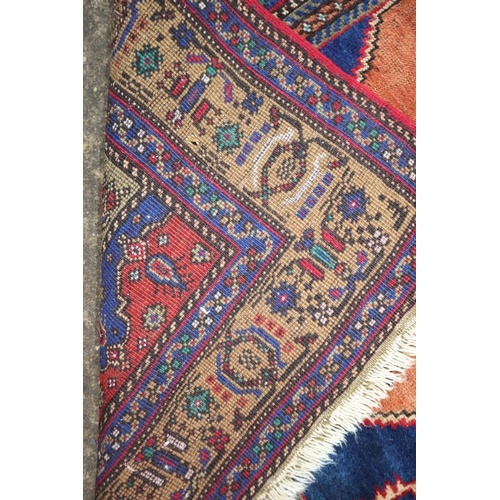 634 - A Persian rug with central figured white medallion on orange and blue grounds and multi-borders, 65