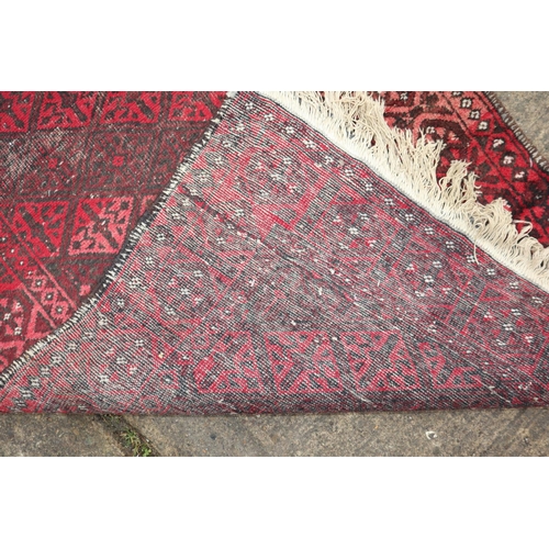 635 - A Baluchi rug with twelve hooked red guls and multi-borders in shades of red, black and white, 60