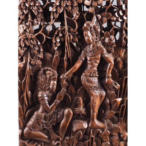 122 - A Balinese hardwood carving, figures amongst trees, 20