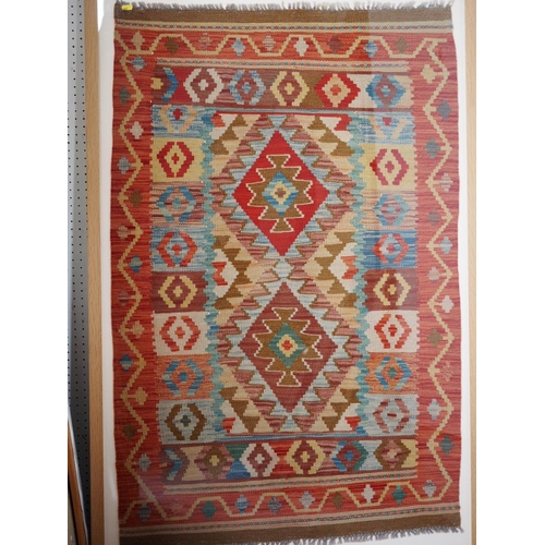 612 - A kelim rug with geometric designs on a red ground in shades of blue, natural, white and orange, 32