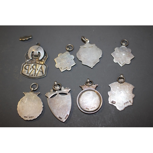 261 - Seven  silver fobs, some with yellow metal mounts, various, 1.8oz troy approx and an ARP badge