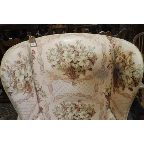 567 - A wing armchair of early Georgian design, upholstered in a glazed chintz, on turned supports (for re... 