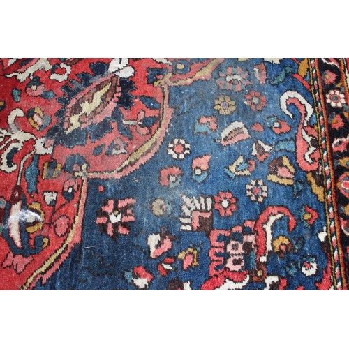 618 - A Persian city rug with all-over tendril and floral design on a red ground, 83