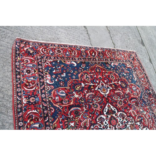 618 - A Persian city rug with all-over tendril and floral design on a red ground, 83