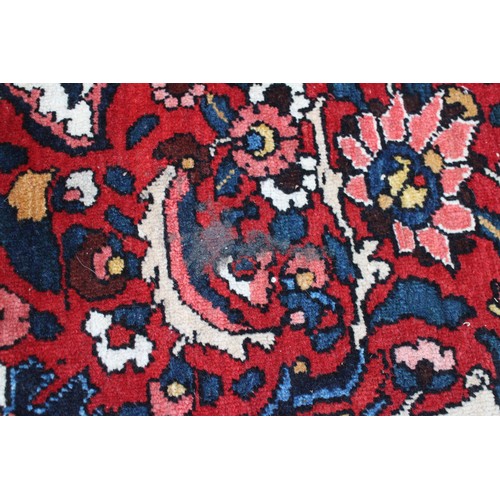 618 - A Persian city rug with all-over tendril and floral design on a red ground, 83