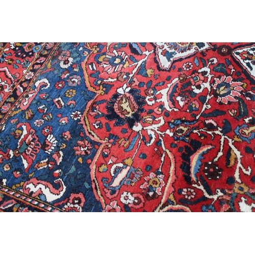 618 - A Persian city rug with all-over tendril and floral design on a red ground, 83