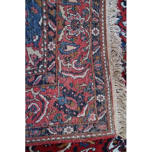 618 - A Persian city rug with all-over tendril and floral design on a red ground, 83