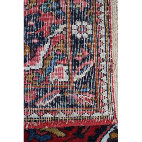 618 - A Persian city rug with all-over tendril and floral design on a red ground, 83