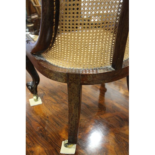 518 - An early 19th century rosewood cane seat and back low seat nursing chair, on cabriole castored suppo... 