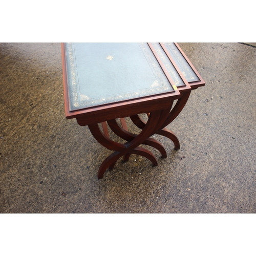 656 - A nest of three mahogany leather top x-frame occasional tables, largest 22
