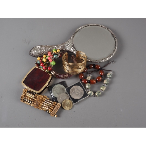323 - A silver backed dressing table mirror with scrolled and floral decoration, beaded bracelets and othe... 