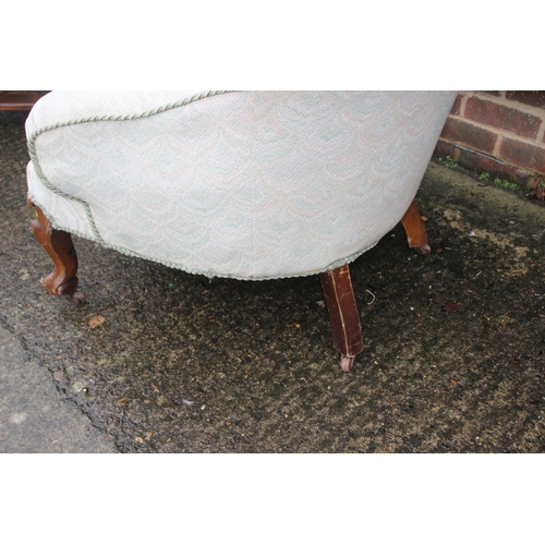 629 - A button back open armchair, upholstered in a patterned fabric, on cabriole castored supports