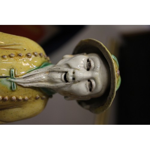 83 - A set of three Chinese yellow, green and brown glazed figures, with stamped marks to bases, 11