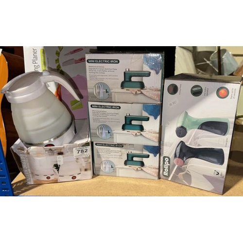 782 - Assortment Of Boxed Travel Electricals Incl Kettle, Irons & Steamer + Slicing Board