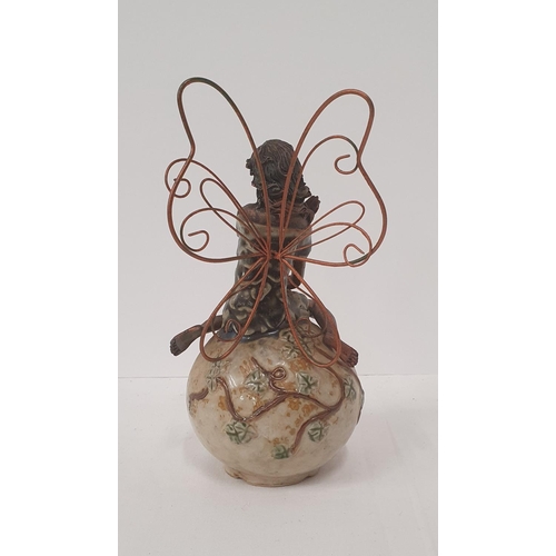 385 - Bronzed effect fairy with metal wings seated on an ovoid rock