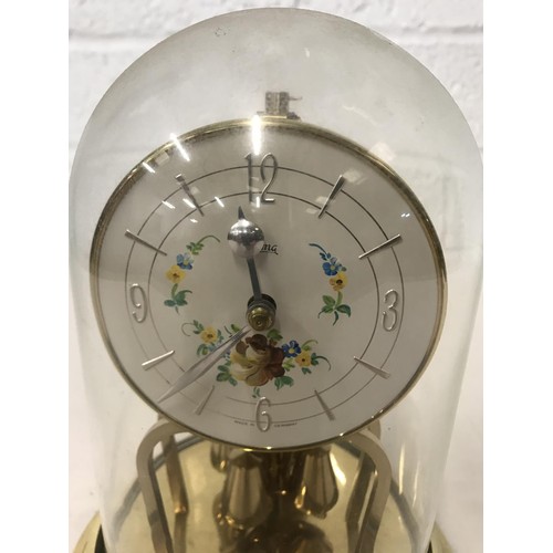 51 - German brass anniversary clock under glass dome with enamel base with floral decoration, white dial ... 