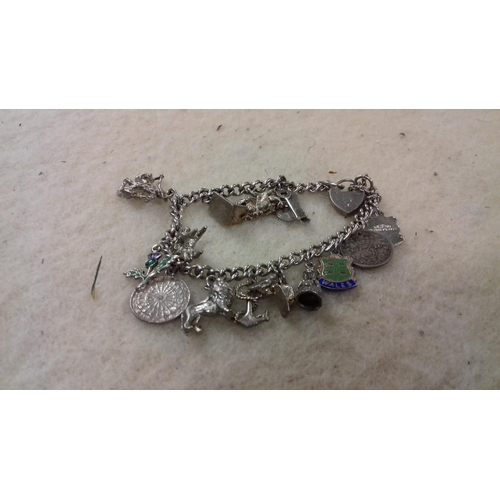 523 - Hallmarked silver charm bracelet with assorted stamped and unstamped charms and coins approx 38 g