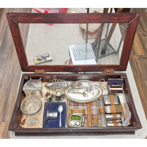 131 - 61.5 x 33.5 x 13 cm glass hinged counter top display cabinet with assorted mostly silver plated misc... 