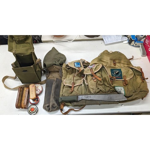 318 - Bundle of military and green canvas camo rucksacks and bags plus 1985 military issue machete in canv... 