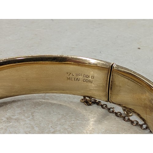 437 - 1/5 9 ct gold metal core bangle with half engraved scrollwork detailing and safety chain - 21.6 gm