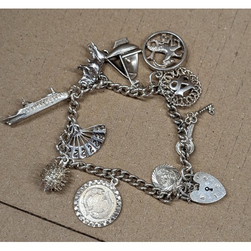 491 - Sterling and hallmarked silver charm bracelet with heart padlock and 11 x assorted charms - 34 gm