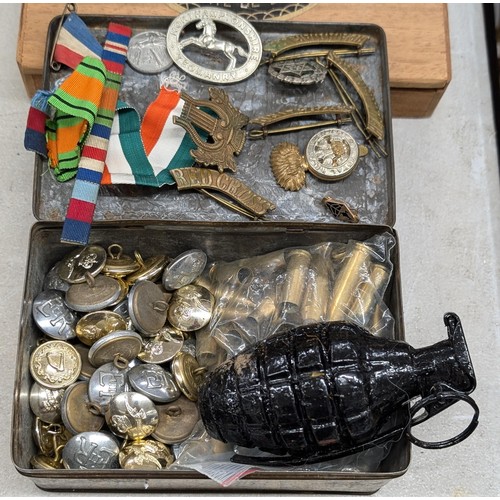 126 - Vintage tin with assorted mixed uniform buttons, badges, empty shell casings and dummy hand grenade