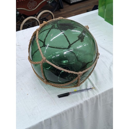 267 - Large vintage glass fishing float in net. Diameter approx 11