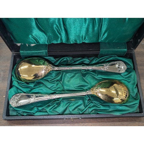 112 - Cased pair of unstamped white metal dessert spoons with gilded bowls