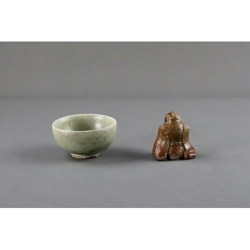 23 - An Amber-glazed Figure and A Celadon Cup, Han dynasty and Sui dynasty a sitting male figure in robe,... 