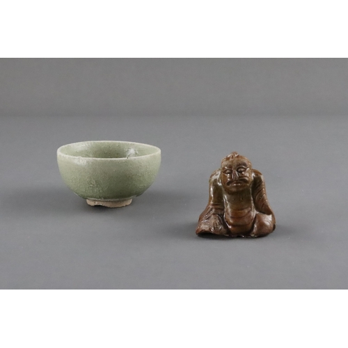 23 - An Amber-glazed Figure and A Celadon Cup, Han dynasty and Sui dynasty a sitting male figure in robe,... 