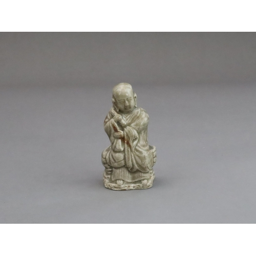 29 - A Rare Miniature Yaozhou Celadon-glazed Figure of a Monk, Song dynasty  The figure wearing long robe... 