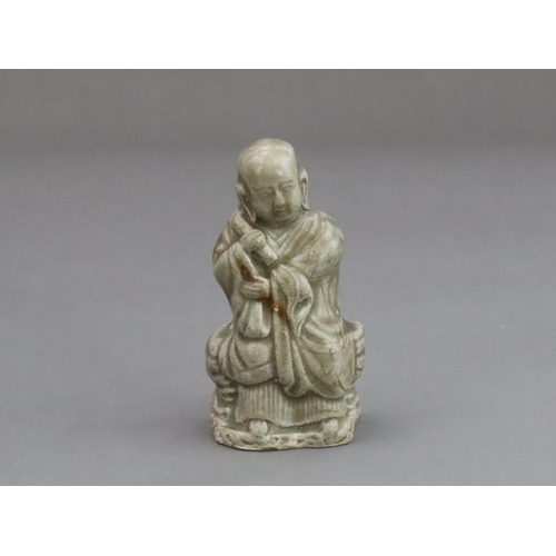 29 - A Rare Miniature Yaozhou Celadon-glazed Figure of a Monk, Song dynasty  The figure wearing long robe... 