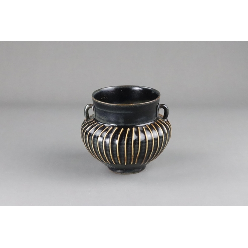 39 - A Cizhou Black-glazed Ribbed Handled Jar, Song dynasty  on a straight foot, the body swelling to the... 