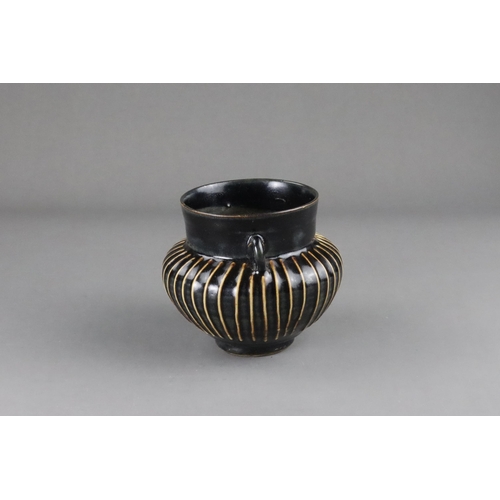 39 - A Cizhou Black-glazed Ribbed Handled Jar, Song dynasty  on a straight foot, the body swelling to the... 