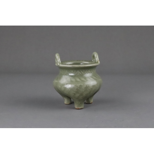 59 - A Carved Longquan Celadon Tripod Incense Burner, early Ming dynasty the compressed body rising from ... 