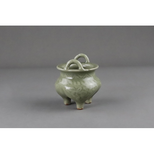 59 - A Carved Longquan Celadon Tripod Incense Burner, early Ming dynasty the compressed body rising from ... 