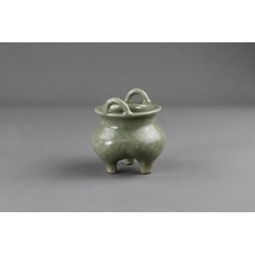 59 - A Carved Longquan Celadon Tripod Incense Burner, early Ming dynasty the compressed body rising from ... 