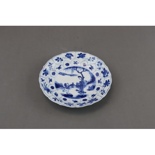 89 - A Blue and White Figural Dish, Kangxi moulded in floral shape, painted in blue and white with a lady... 