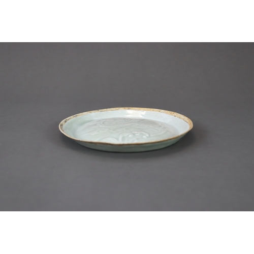 38 - A Qingbai moulded 'Dragon' Dish, Song/Yuan dynasty thinly potted, the slightly convex interior mould... 