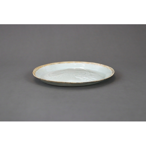 38 - A Qingbai moulded 'Dragon' Dish, Song/Yuan dynasty thinly potted, the slightly convex interior mould... 