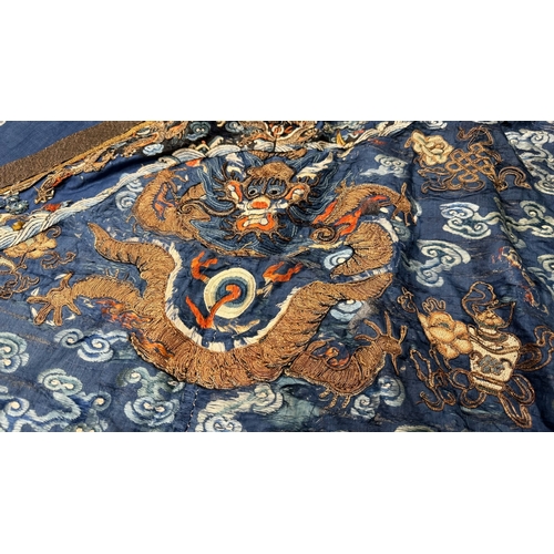 135 - An Embroidered Blue Ground Dragon Robe, 19th century with golden dragons among clouds, interspersed ... 