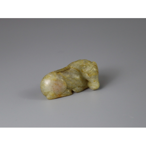 192 - A Jade Seated Horse, 17th century,  softly carved from a greyish celadon stone with faint russet suf... 