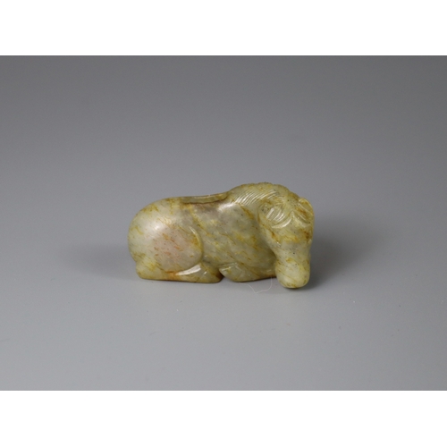 192 - A Jade Seated Horse, 17th century,  softly carved from a greyish celadon stone with faint russet suf... 