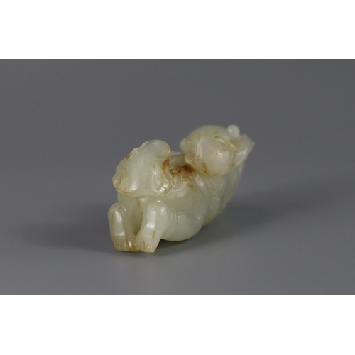 193 - A Pale Celadon Jade Boy, 18th century,  finely carved with the smiling reclining boy holding a leafy... 